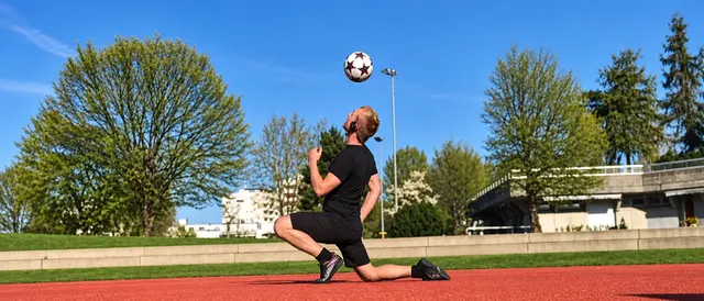 Kniend mit Ball in der Luft