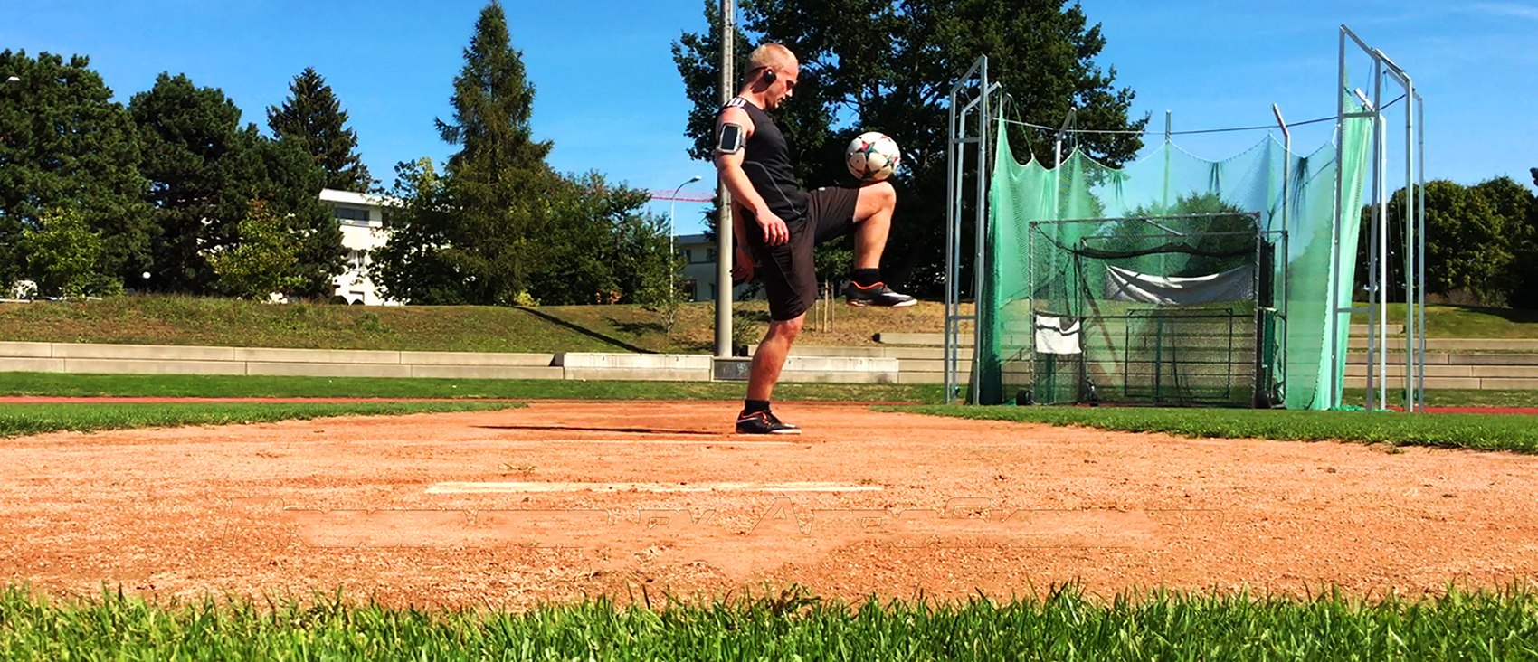 Aeroskiller jongliert den Ball mit dem Knie auf einem sonnigen Sportfeld — dynamische Freestyle-Football-Kontrolle.
