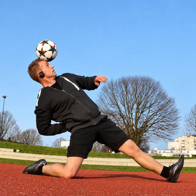Ausfallschritt mit Ball auf rotem Platz